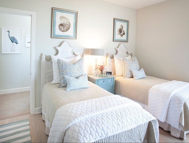Two white beds with pale blue pillows and a blue bedside table between them.
