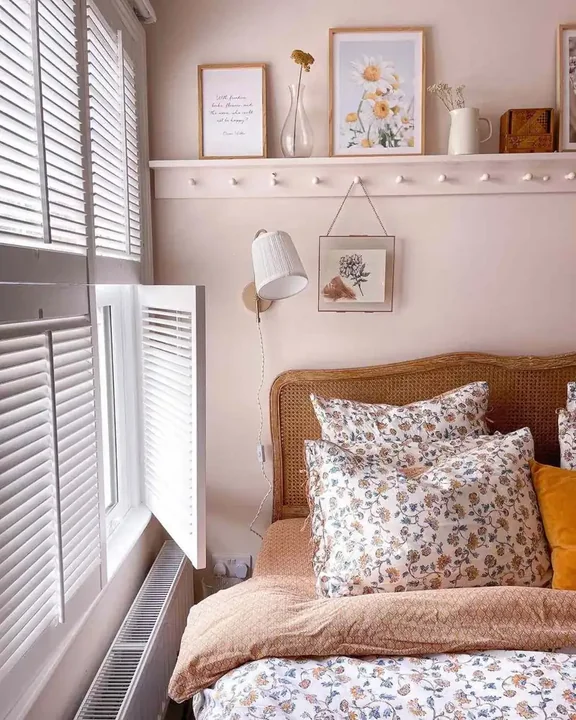 A pleated wall light hangs above a woven headboard in a pink bedroom.