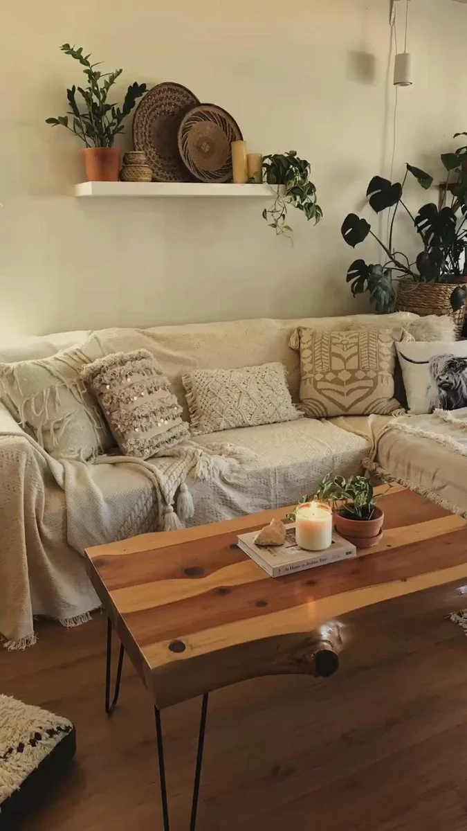 Cream sofa with textured pillows beneath a shelf of woven trays and plants