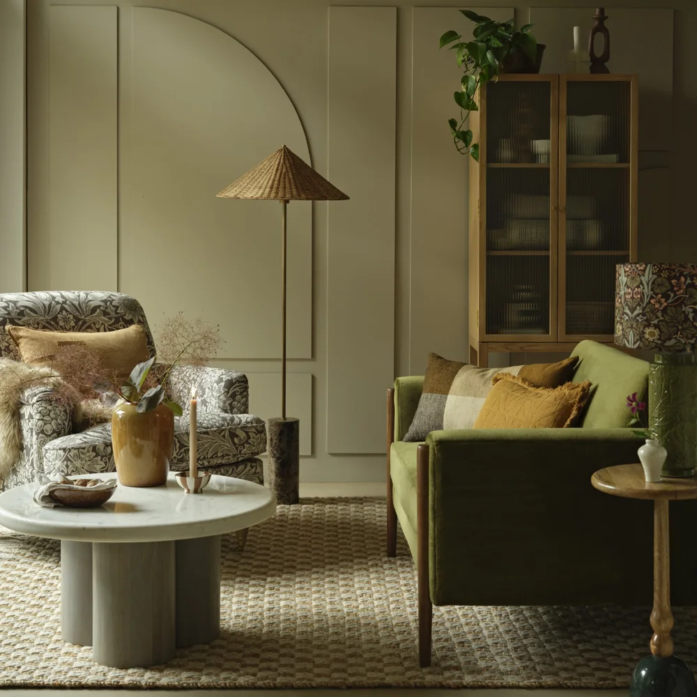 An olive-green room has green seating, a patterned armchair, yellow cushions, and a pale rug.