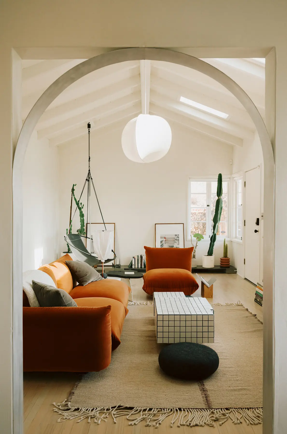 An orange sofa and armchair sit to the left of a clear route along the right wall.