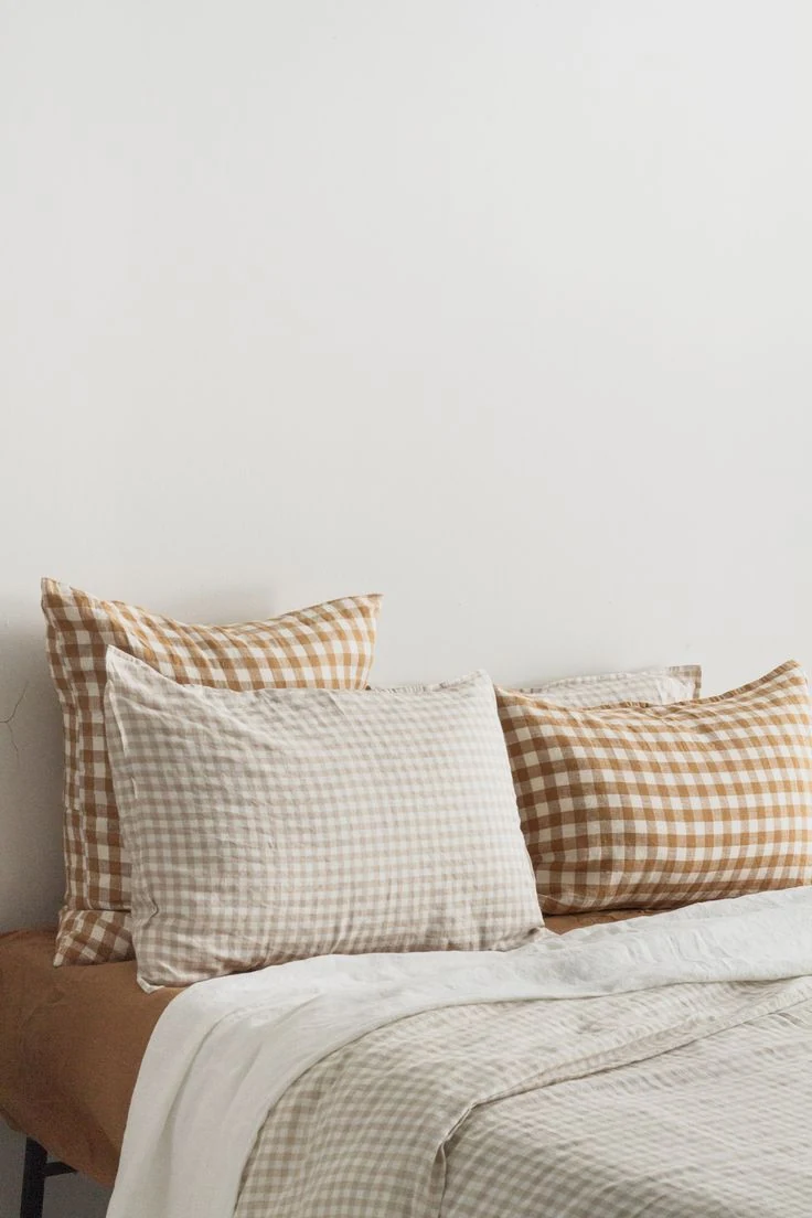 Caramel-and-white checked pillows sit behind paler small-check pillows above softly checked bedding.